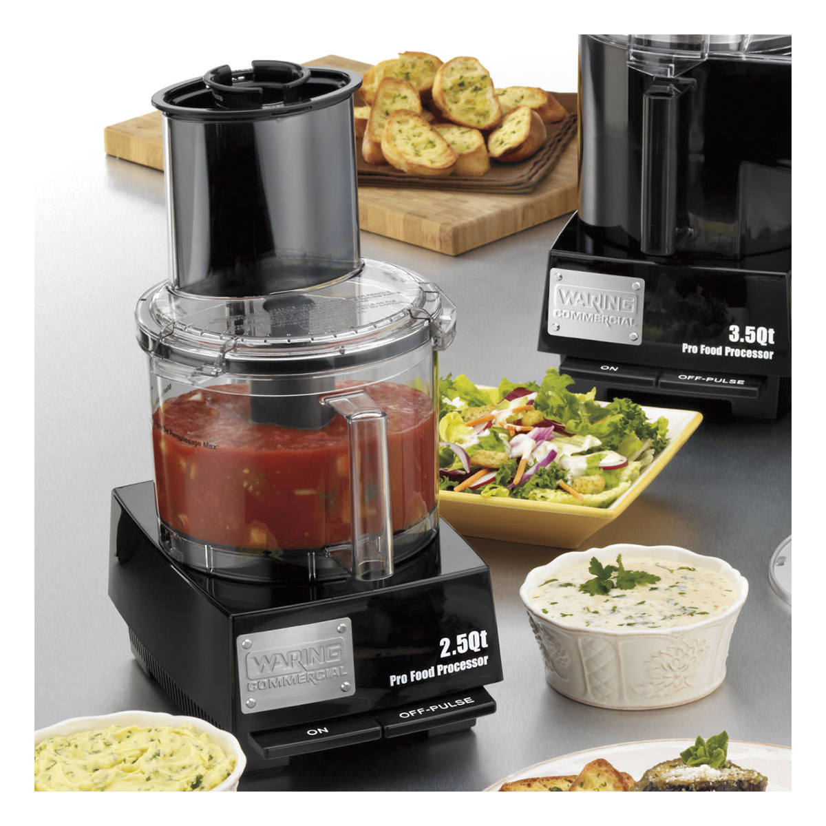 Waring WFP11S food processor in a kitchen setting with prepared dishes