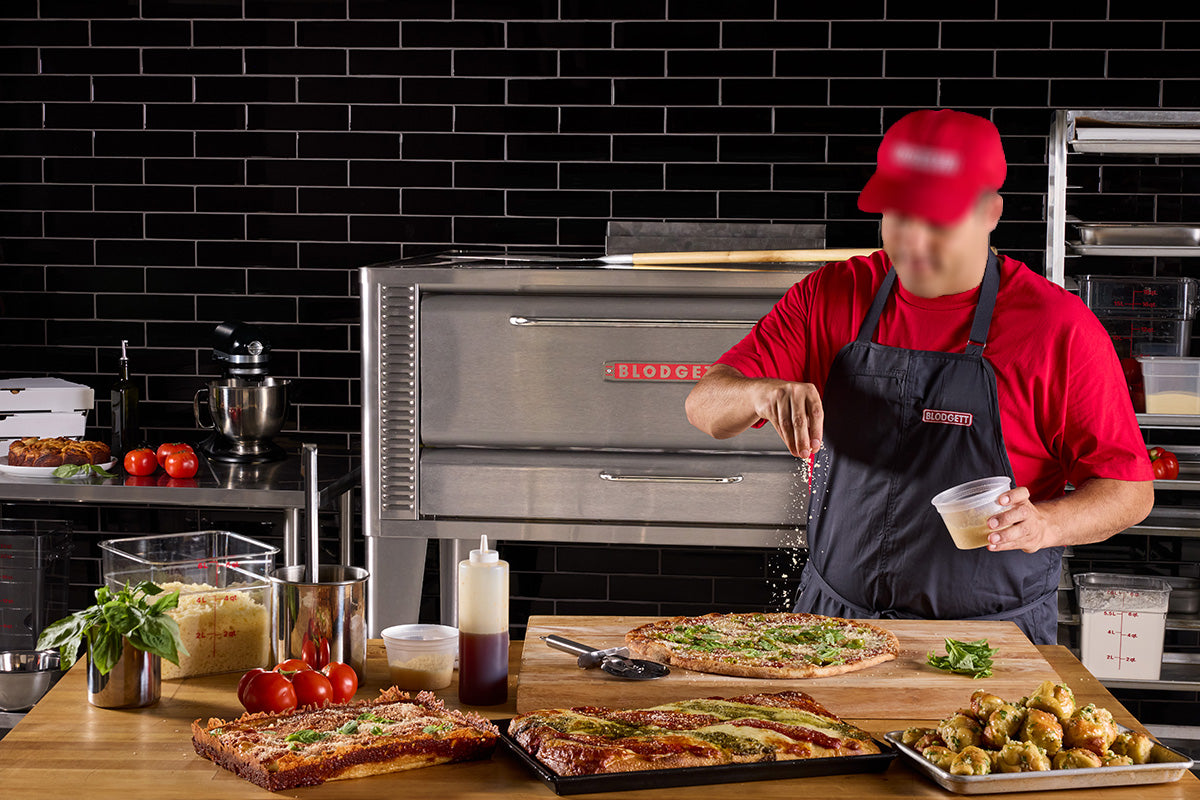Chef preparing pizzas in front of a Blodgett gas pizza deck oven