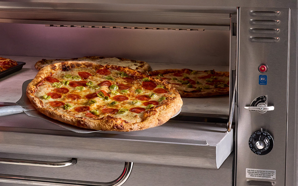 Pizza on a peel at an open Blodgett deck oven, close-up (representative image)